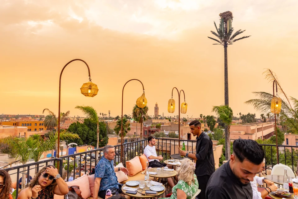 Camarero atendiendo a los clientes bajo los faroles con vistas a la Koutoubia
